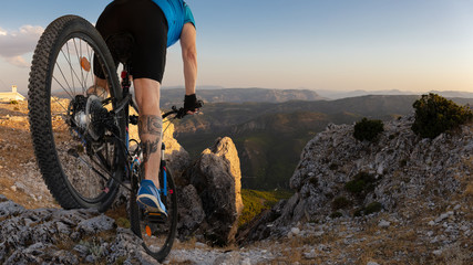 A mountain biker descends into a gorge from the top of Mount Ardal in Spanish Castille. It is just before sunset and the views of the landscape are great.