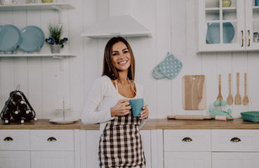 Young beautiful business woman drinking her coffe and smiling in the kitchen