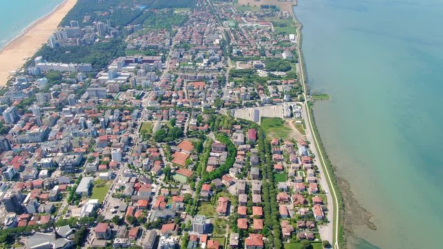 Aerial tilt revealing Lignano Sabbiadoro town located on a narrow strip of land surrounded by water