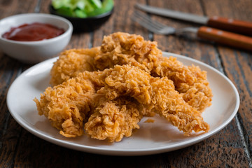 Crispy fried breaded chicken strips on plate and ketchup
