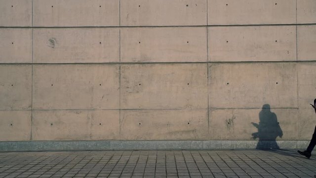Full length view in slow motion of young business people employees walking and talking to each other against copy space wall where you can paste advertising .Colleagues using smartphone communicating