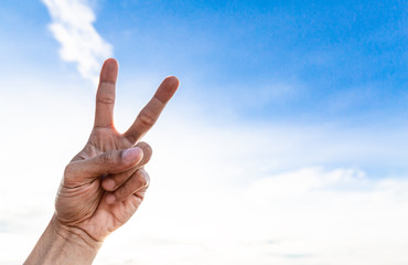 Man's hand showing two fingers up on sky