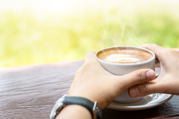 Close up hand of woman holding a cup of hot coffee