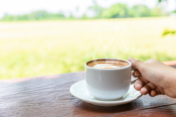Close up hand of woman holding a cup of hot coffee