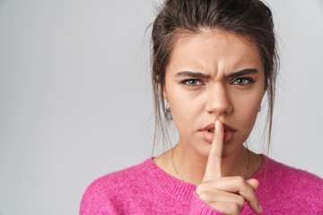 Image of nice annoyed woman in pink sweater gesturing silence sign