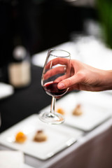 Verre de vin dans une main de femme avec une table blanche en fond