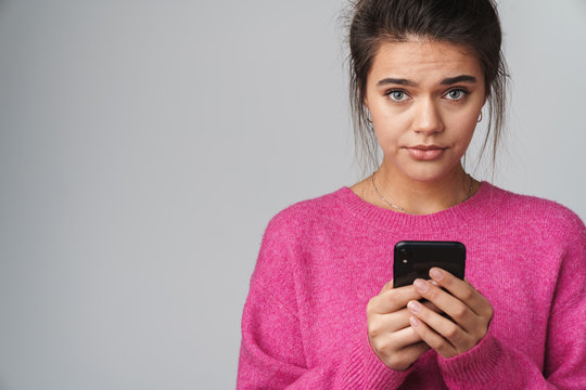 Image of unhappy beautiful woman using cellphone and looking at camera