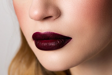 Fototapeta premium Girl's lips with matte lipstick burgundy color.