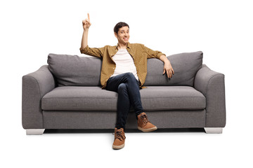 Young man sitting on a sofa and pointing up