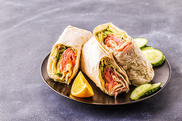 Wrapped sandwich with salmon, lettuce, cucumber and cream cheese.