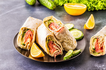 Wrapped sandwich with salmon, lettuce, cucumber and cream cheese.