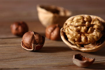 hazelnuts and walnuts with split shells on a wooden table close-up