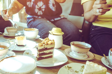 Happiness female friends meeting and drinking tea or coffee with cakes together at cafe in the afternoon. People, leisure and communication concept. Selective focus.