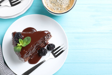 Delicious chocolate cake with blackberries on light blue wooden table, flat lay. Space for text