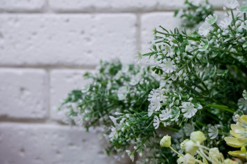 Artificial flower arrangement in flower shop with brick wall. .
