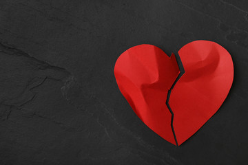 Torn paper heart on black stone background, top view with space for text. Relationship problems...