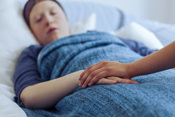 Sick young girl suffering from lungs cancer with friend supporting her