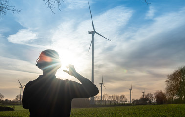 Engineer standing in front of a wind turbine during sunset.