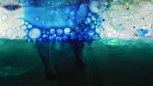 Abstract colored background: spread of blue ink in the liquid near the surface with bubbles