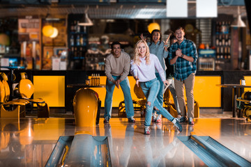 smiling girl looking at skittle alley near excited multicultural friends