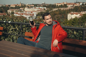 Man drinking beer. Handsome young hipster man drinking beer while sitting at the bar outdoors with...