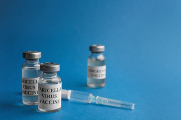 Chickenpox vaccine and syringe on blue background. Varicella virus prevention