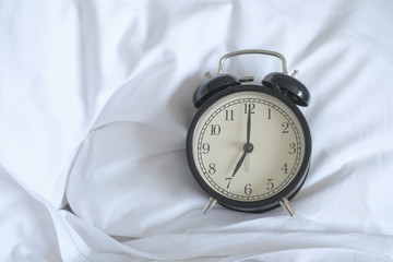 Alarm clock on white bed with copy space for you design..