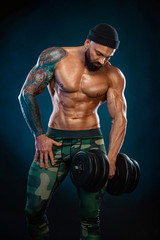 Man athlete bodybuilder. Muscular young fitness sports guy doing workout with dumbbell in fitness gym