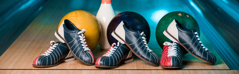 panoramic shot of bowling shoes, balls and skittles in bowling club