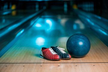 selective focus of bowling shoes and ball on skittle alley in bowling club - obrazy, fototapety, plakaty