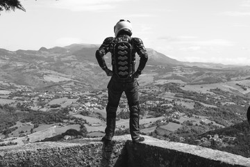 Man dressed in a motorcycle outfit. body protection turtle, knee pads and helmet. Standing on the...