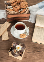 A cup of tea with oatmeal cookies and crackers. 