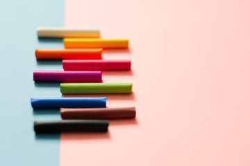 Colorful pastel crayons on pink geometric background with copy space. Art, drawing concept