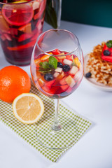 Red wine fresh sangria or punch with fruits, mint leaves and berries. Homemade waffles on the background.
