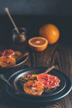 Orange dessert with wine honey or maple syrup and ginger spice, decorated pomegranate berries. Wonderfully sweet, rich and fresh food. Dark rustic background, copy space for you text