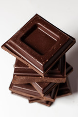 Dark chocolate pieces isolated on white background. Top view.