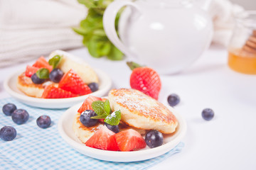 Cottage cheese pancakes, syrniki with berries and powdered sugar.