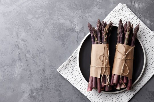 Fresh purple asparagus in black plate - Powered by Adobe
