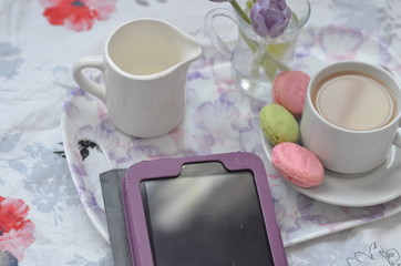 Obraz na płótnie Canvas tablet with cup of coffe on tray and spring flowers on pink bedding. Relaxing, or working, or writing diary or blog in bed at home. with tablet
