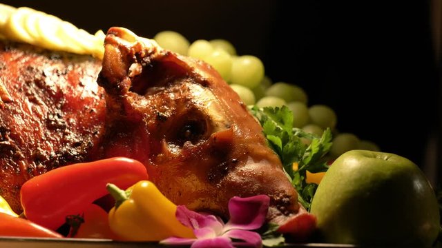 Close up of roast pig head on plate with veggies