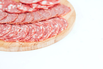 Thin slices of sausage on a wooden board copy space. Sliced ​​Salami.