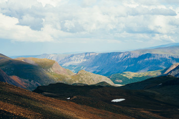 Different climate in one vast mountain landscape at different heights and distances. Aerial alpine landscape with wasteland on high altitude and forest in highland valley. Wonderful vastness scenery.