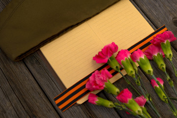 9 May holiday. Victory Day background. George ribbon, old military cap and red flowers. Symbol of 9...