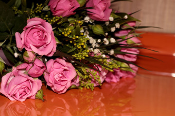 Green bouquet with small roses on an orange background. Pink small roses.