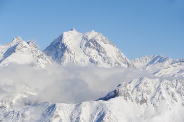 Snowy mountain peak with clouds and fog in ski resort Courchevel French Alps.