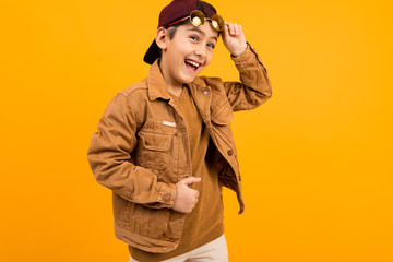 european funny teenager boy in casual stylish brown denim jacket and stylish glasses on a yellow background