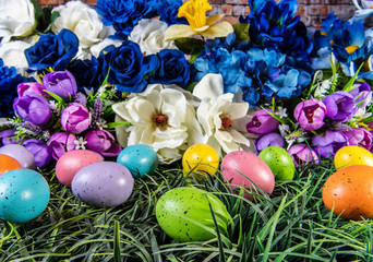 colored Easter eggs in green grass with spring flowers