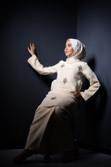 Hijab beauty and fashion editorial concept. A beautiful Muslim model in modern kurung and hijab in various editorial poses for a studio photoshoot. Full length portrait.