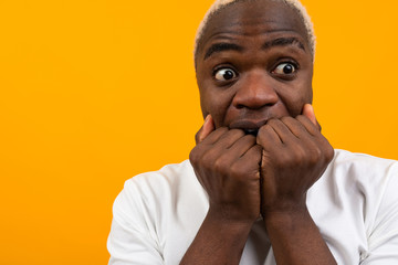 portrait of an african black man covering his mouth in surprise on a yellow background with copy space