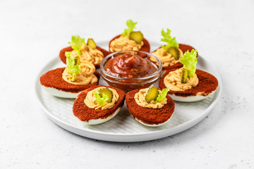 Easter appetizer, bloody mary deviled eggs with pickles and bbq sauce. Selective focus, copy space.